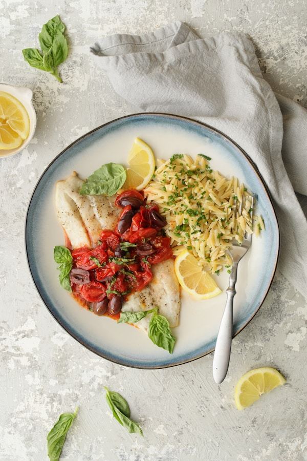 Baked Fish with Cherry Tomato-Olive Sauce and Lemon Chive Asiago Orzo Recipe | HeyFood — heyfoodapp.com
